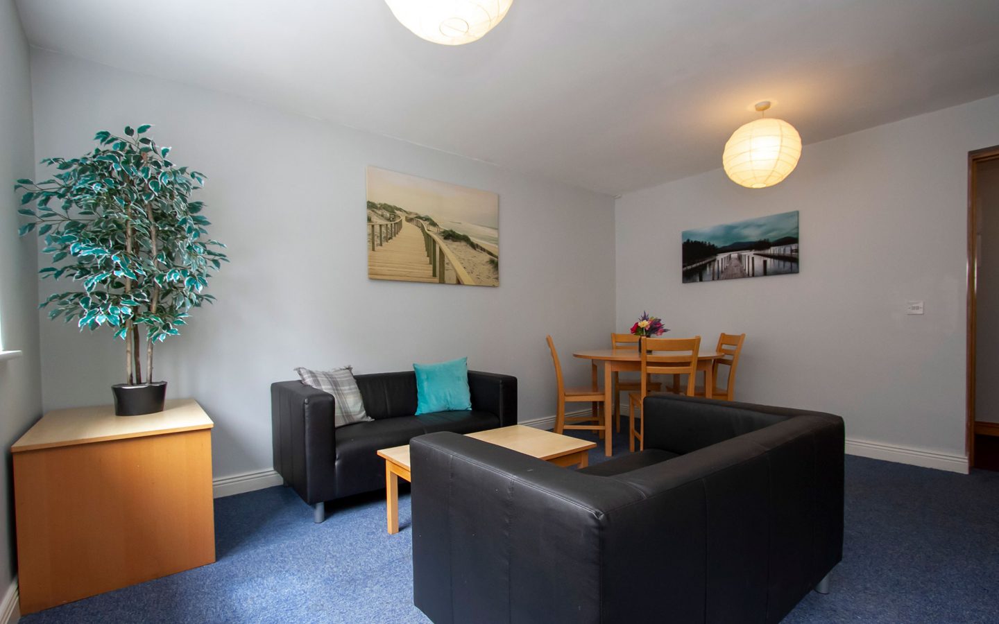 Bright shared living room with sofas, dining table and artwork